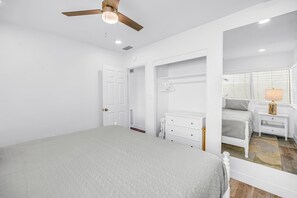 A bedroom with a bed, a dresser, a nightstand, a ceiling fan, and a window with blinds. - Gertrude's Siesta | Private Patio, Pool,  2-min to Beach! 1-min Dining & Music! (Siesta Key)