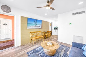 A modern interior with a wooden bench, a round coffee table, and a blue patterned rug. - Gertrude's Siesta | Private Patio, Pool,  2-min to Beach! 1-min Dining & Music! (Siesta Key)