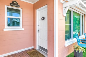 A house with a white door, a window with a sailboat sign, and a porch with blue chairs. - Gertrude's Siesta | 100% Private, 2-min to Beach Path! Dining & Music! Snorkeling, Sunsets! (Siesta Key)