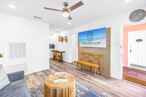 A modern living room with a ceiling fan, a dining area with a table and chairs, and a wall-mounted artwork. - Gertrude's Siesta | 100% Private, 2-min to Beach Path! Dining & Music! Snorkeling, Sunsets! (Siesta Key)