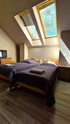 Quarto com cama, escrivaninha e dois claraboias.