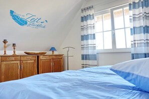 Ein Schlafzimmer mit einem Bett, einer Holzkommode und einer Wanddekoration.