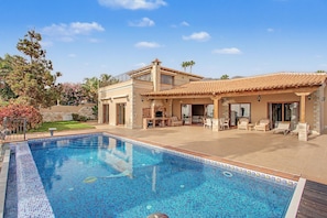 A two-story house with a swimming pool, outdoor seating area, and a patio.