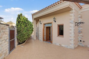 A building with a tiled patio, a wooden door, and a stone wall. - Villa Samarin – Golf & Ocean View (Adeje)