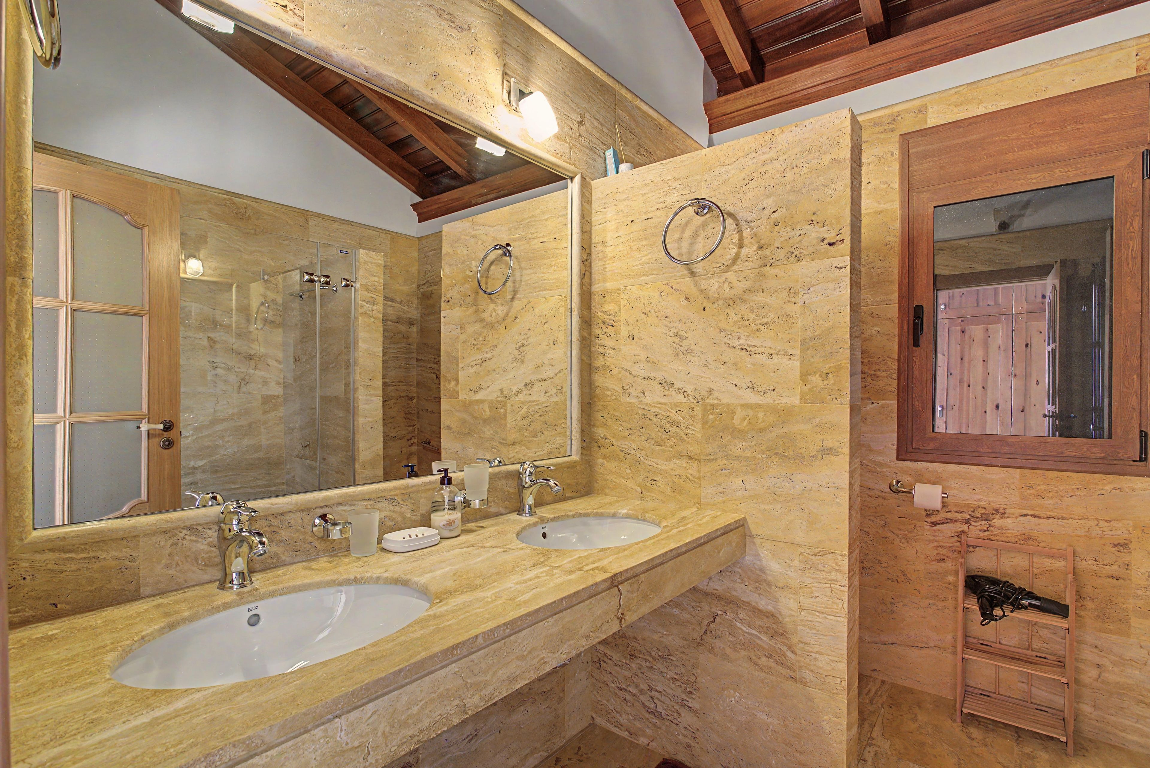 Een badkamer met twee wasbakken, een spiegel en een houten wastafelmeubel.