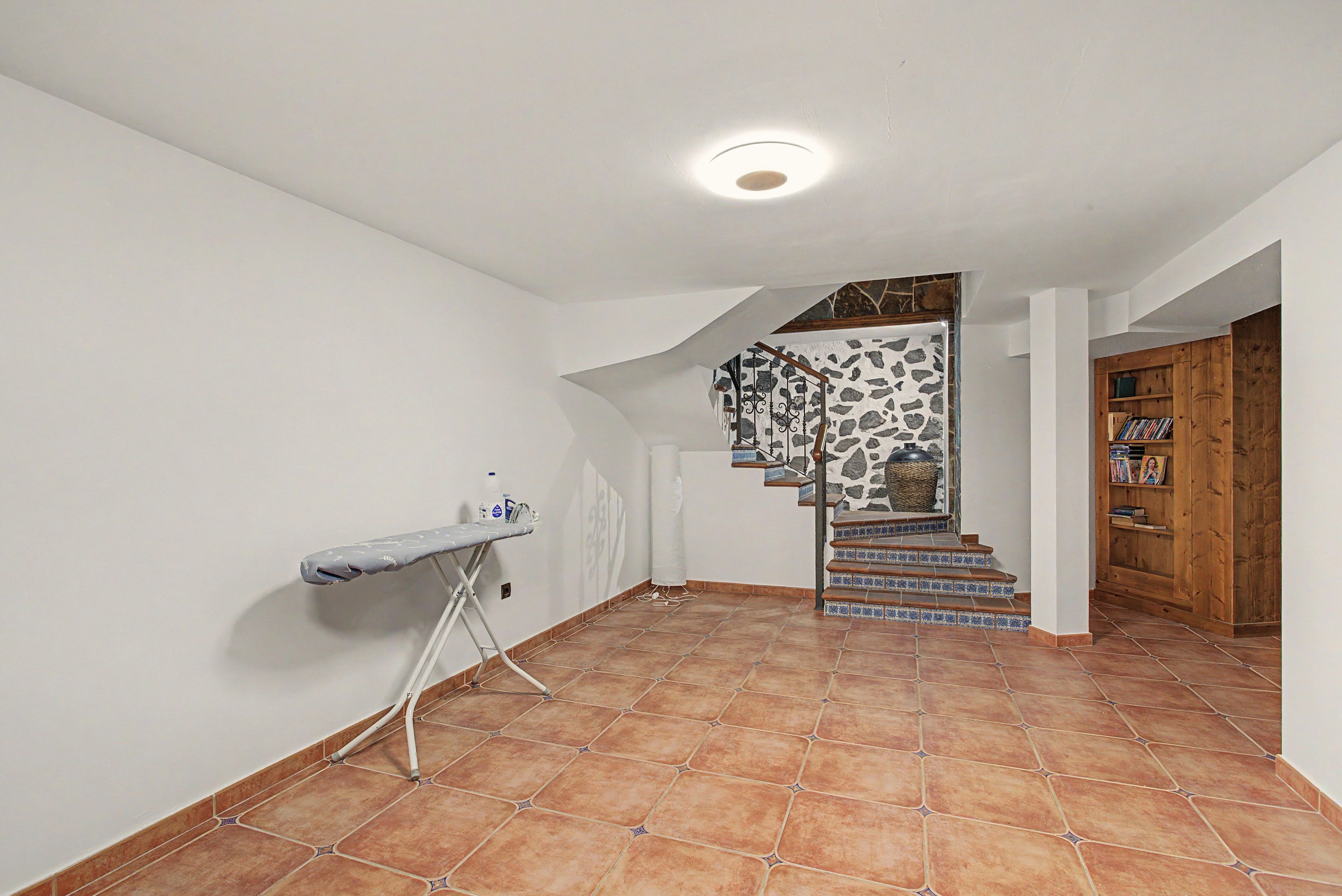 A staircase with blue and white tiles leading to a landing with a stone wall.