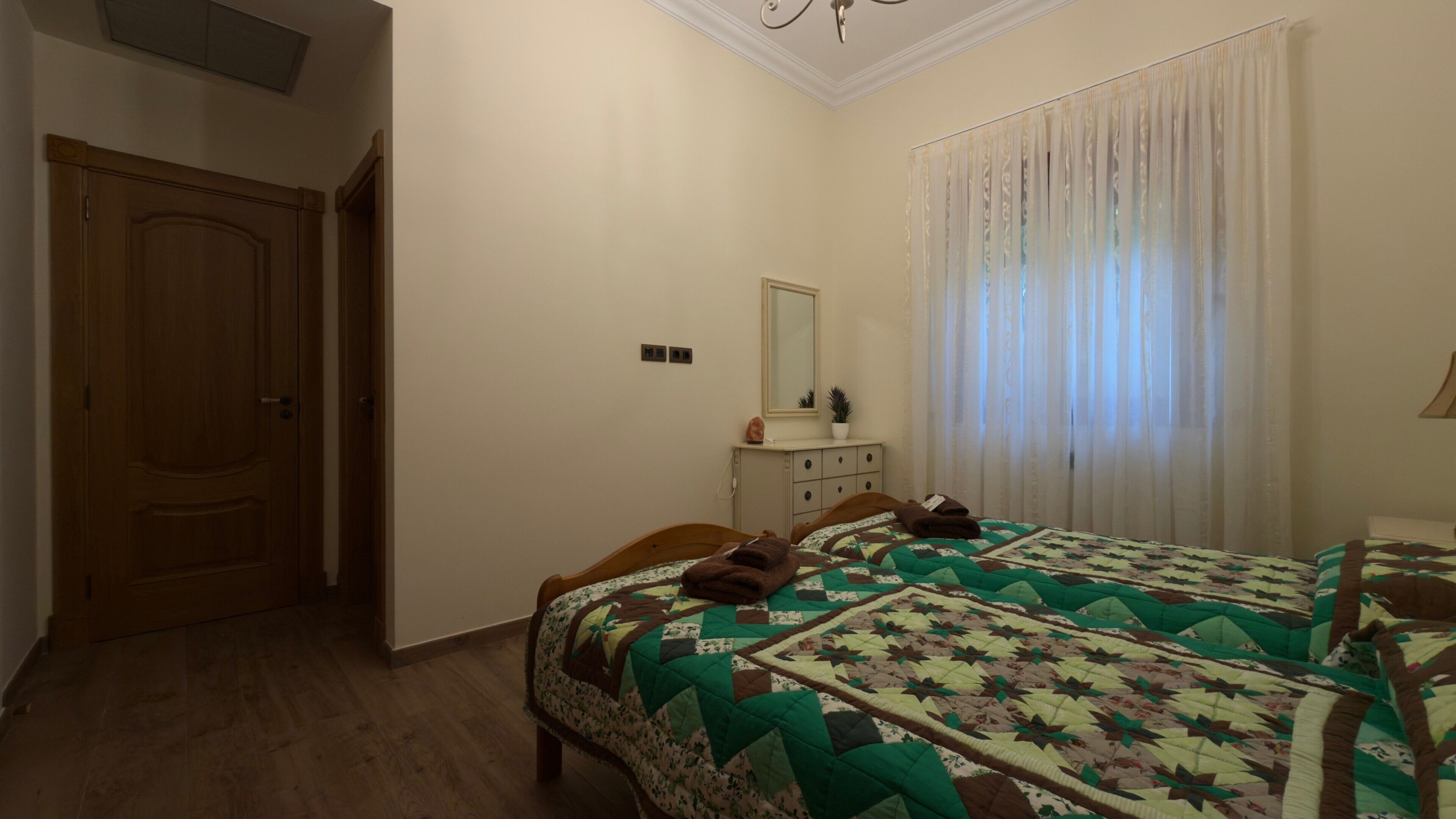 Un dormitorio con dos camas, un aparador, un espejo y una ventana con cortinas.