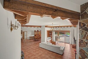 A spacious living room with a white sofa, wooden ceiling beams, and a view to the outside. - Villa Samarin – Golf & Ocean View (Adeje)