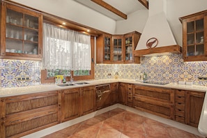 A kitchen with wooden cabinets, a tiled backsplash, and a window with curtains.