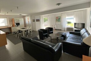 A modern living room with a sofa, chairs, a dining table, and a TV. - Holiday apartment with terrace (RYN)