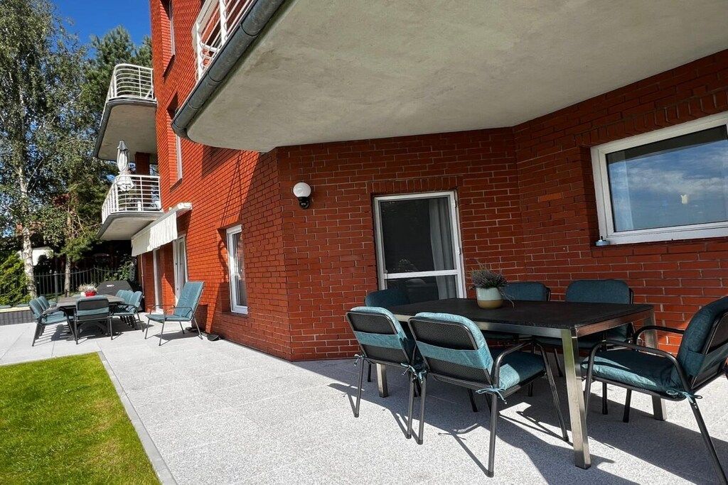A patio with a table and chairs, a brick building, and a window.