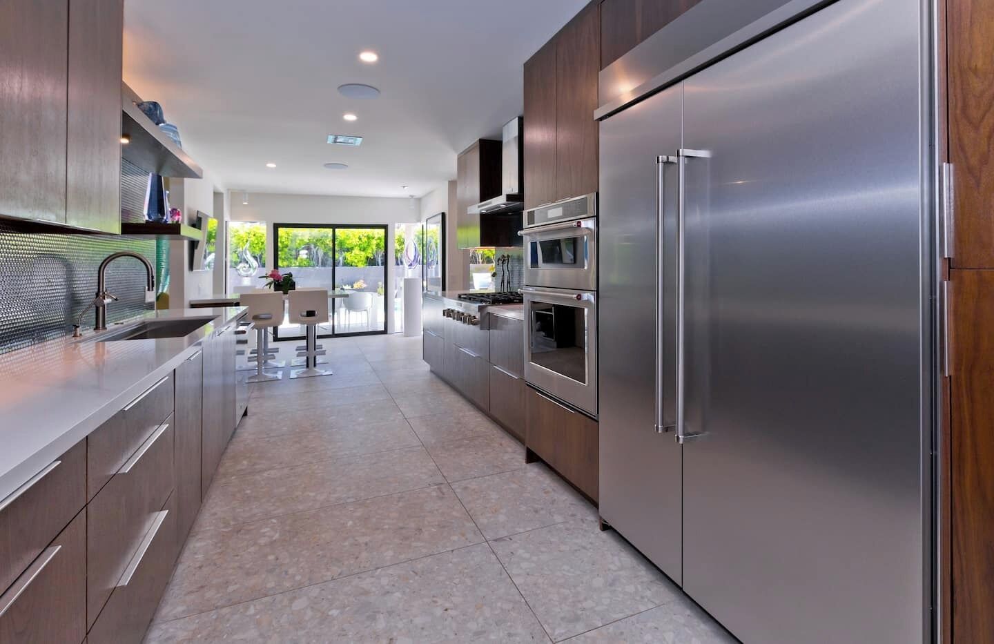 A modern kitchen with stainless steel appliances, a dining area with a view, and a large window.