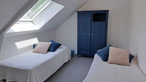Een kamer met twee bedden, een kledingkast en een dakraam.