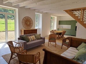 A spacious living area with a sofa, chairs, a dining table, and a kitchen in the background. - Vrbo Property (Le Guerno)