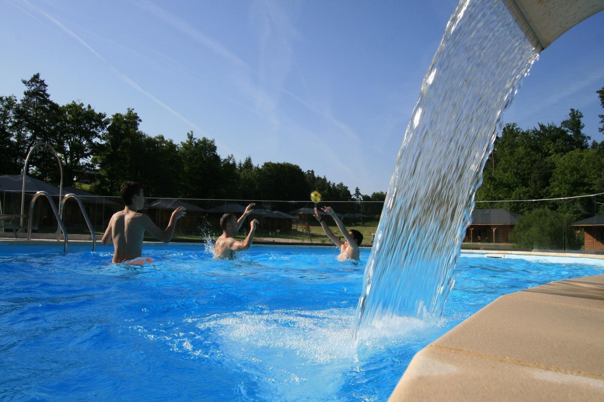 A swimming pool with water being poured from a structure above.