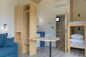 A compact room with a bunk bed, a small table, a sofa, and a kitchenette. - 4-Person Lake View Cabin (MEYRIGNAC  L'EGLISE)