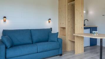 A room with a blue sofa, wooden shelving unit, and a small table.