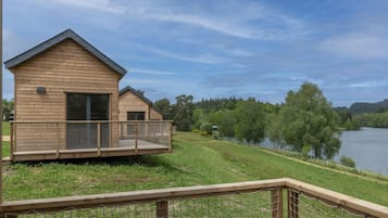 A wooden cabin with a balcony overlooking a lake, surrounded by trees.