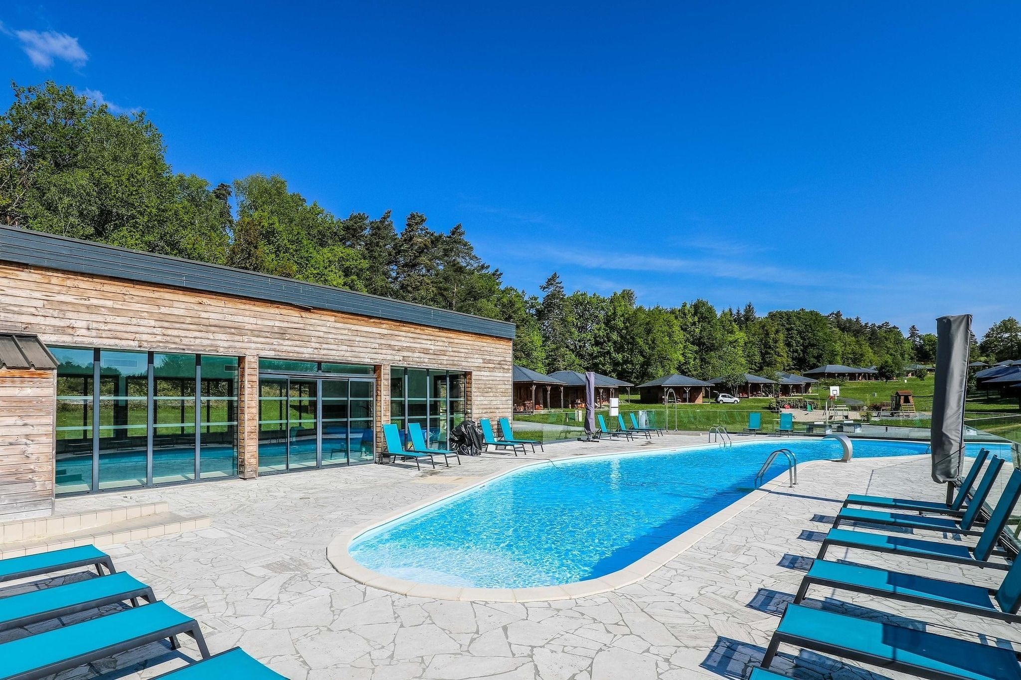 Un espace piscine avec des chaises longues et un bâtiment doté de grandes fenêtres.