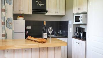 A kitchen with a wooden countertop, a bottle of wine, a wine glass, and a loaf of bread.