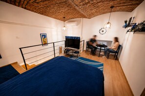 A room with a bed, a TV, a small table, and chairs.