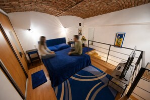A room with a bed, a desk, a chair, a TV, and a staircase. - Cozy 1-bedroom apartment in Budapest (Budapest)