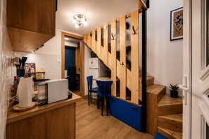A compact kitchen with a wooden counter, a blue chair, and a staircase with wooden steps.