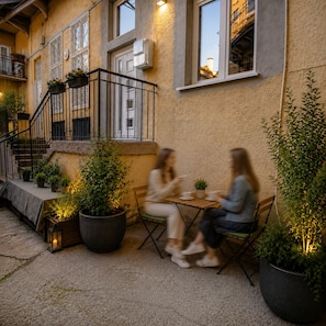 An outdoor seating area with tables and chairs, potted plants, and a staircase leading to an upper level. - Cozy 1-bedroom apartment in Budapest (Budapest)