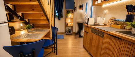 Une cuisine moderne avec des meubles en bois, un lave-vaisselle intégré et un coin bar équipé d’une machine à café.