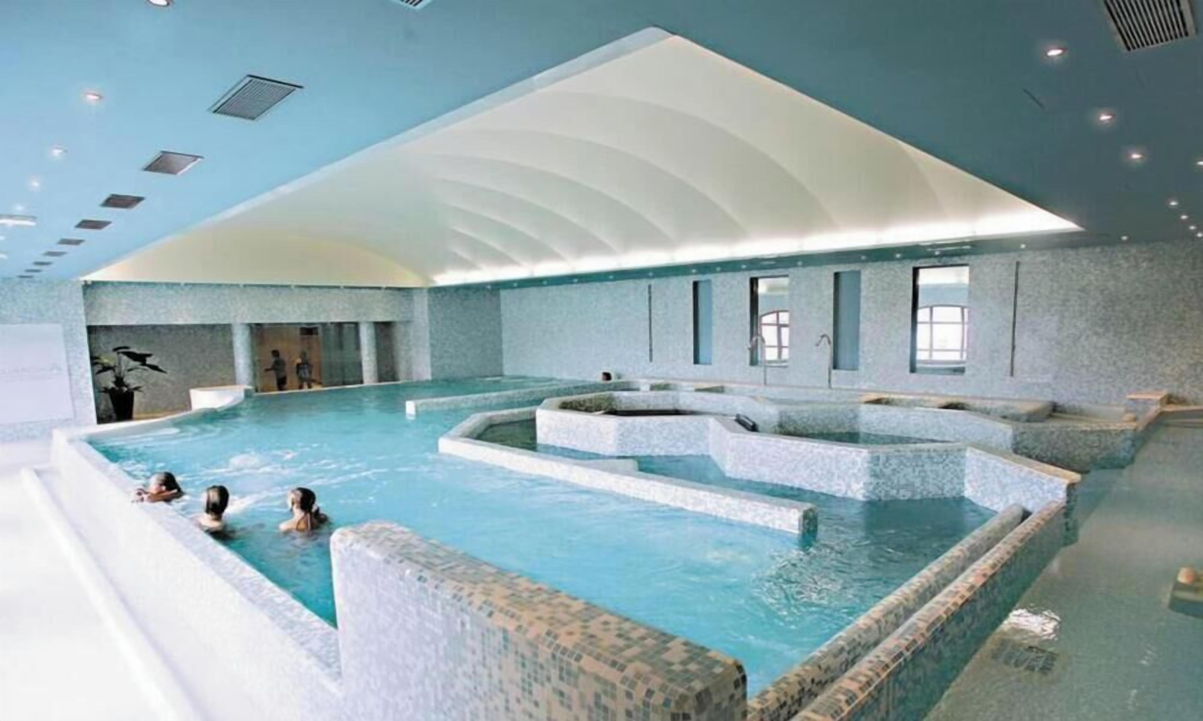 A large indoor swimming pool with multiple levels and a high ceiling.