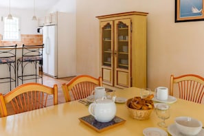 A dining area with a table set for two, a cabinet with glass doors, and a kitchen in the background. - Cabin House for 4 in Provence (Fayence)