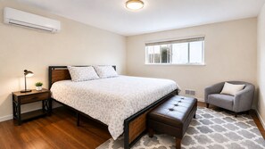 A bedroom with a bed, bedside table, lamp, chair, and window. - 2BR/2BA in Queen Anne | Near Downtown Seattle Center I AC and driveway parking (Seattle)