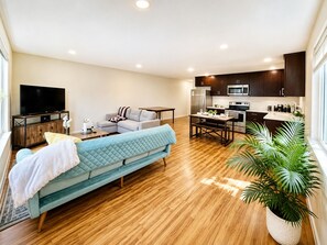 A modern living room with a sofa, a television, and a dining area with a table and chairs. - 2BR/2BA in Queen Anne | Near Downtown Seattle Center I AC and driveway parking (Seattle)