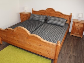 Ein hölzernes Bett mit Kopfteil, zwei Nachttische und ein grüner Teppich.