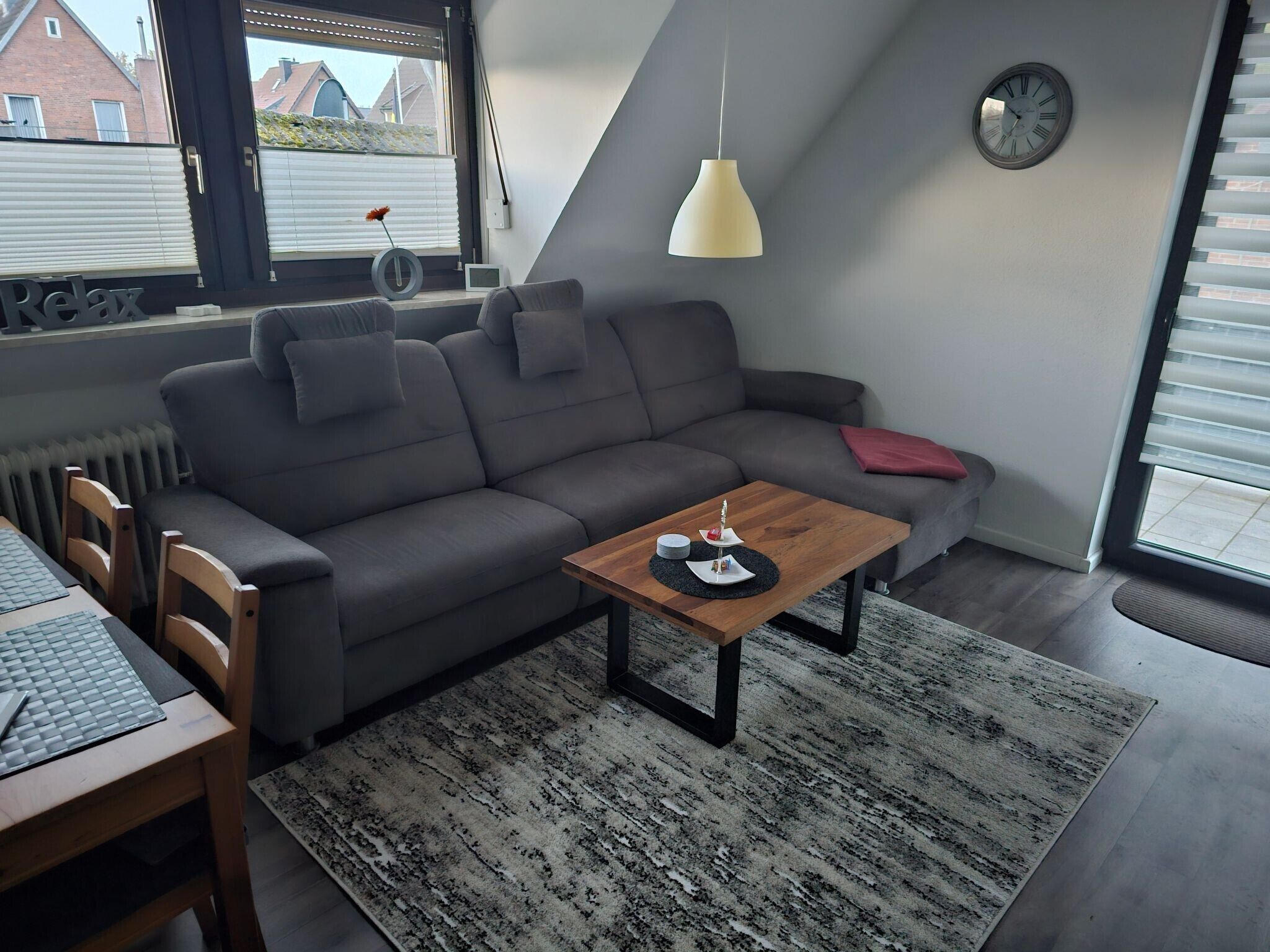 A modern living room with a grey sofa, a wooden coffee table, and a black and white patterned rug.