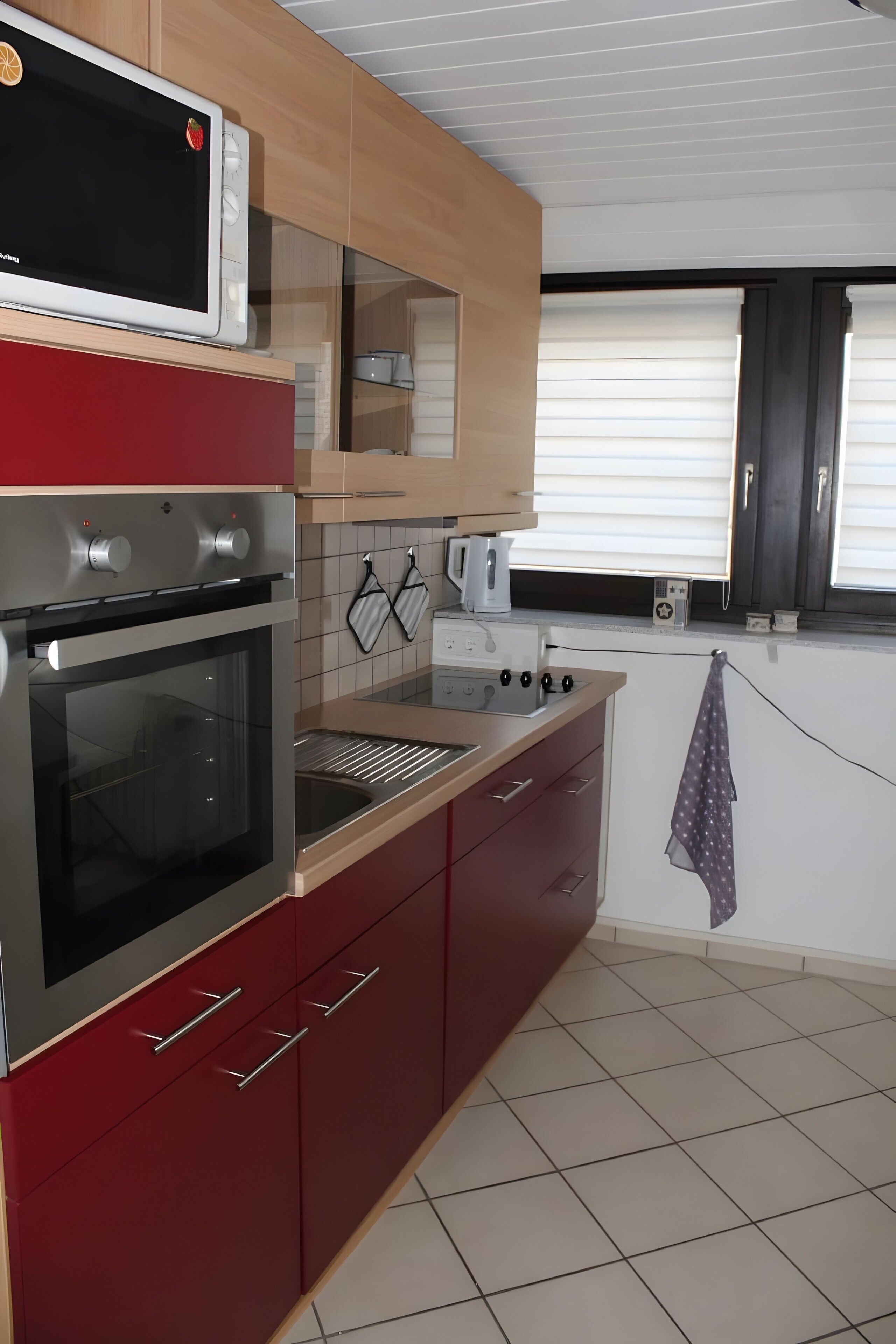 Una cocina con horno empotrado, microondas y cafetera.