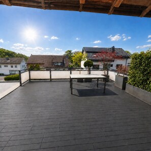 Un'area patio all'aperto con tavolo e sedie, circondata da un muretto e vasi con piante.