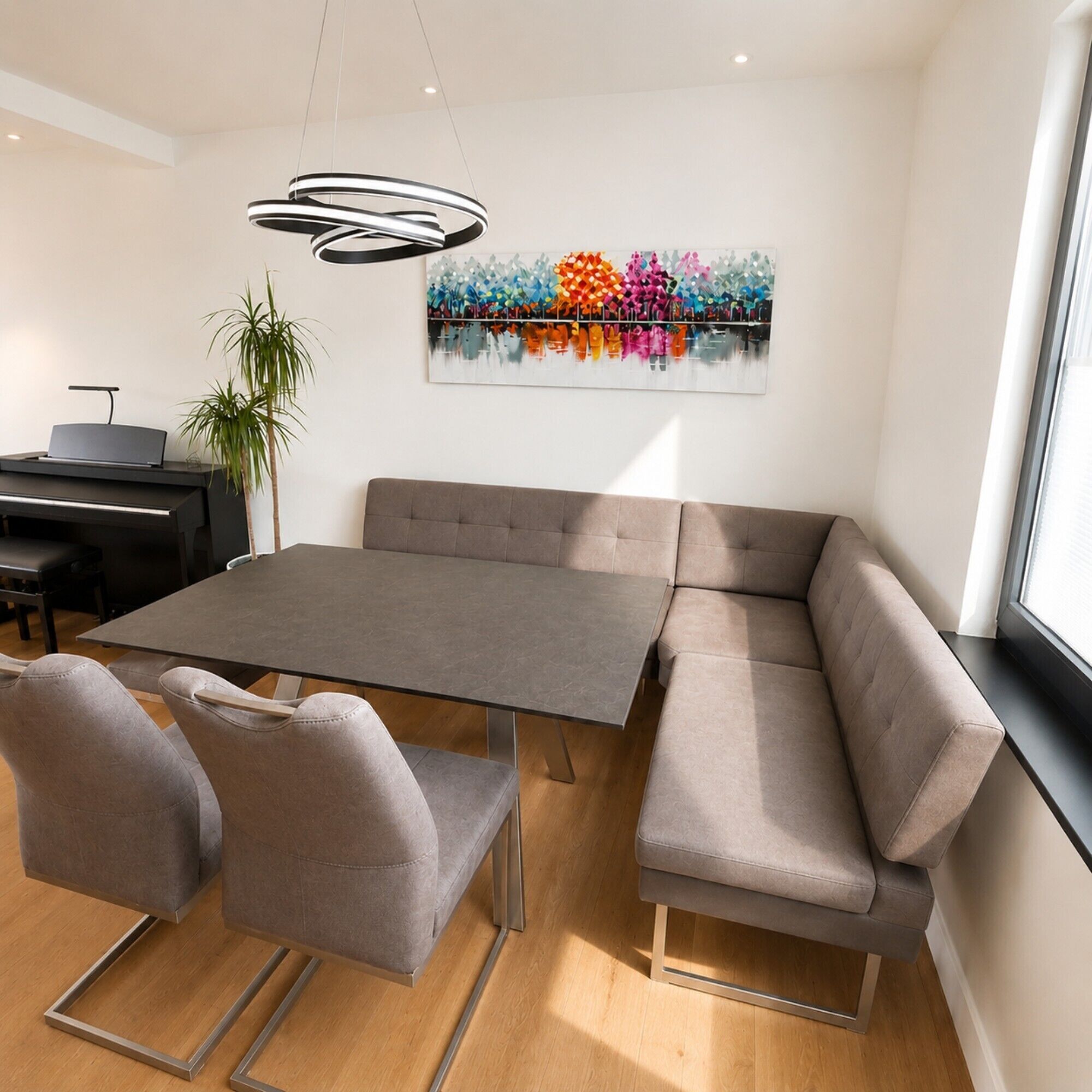Uma zona de refeições moderna com uma mesa cinzenta, duas cadeiras cinzentas, um sofá e um piano.