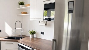Eine moderne Küche mit Edelstahlgeräten, weißen Schränken und einer Holz Arbeitsplatte.