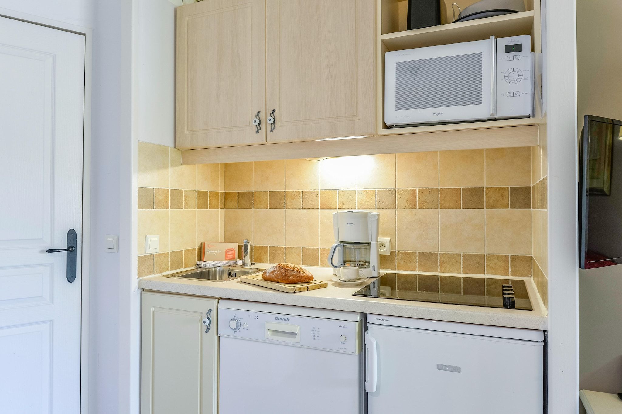 A compact kitchen with a dishwasher, a coffee maker, and a microwave.