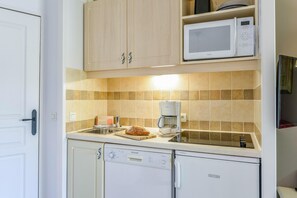 Une cuisine compacte équipée d’un lave-vaisselle, d’une machine à café et d’un four à micro-ondes.