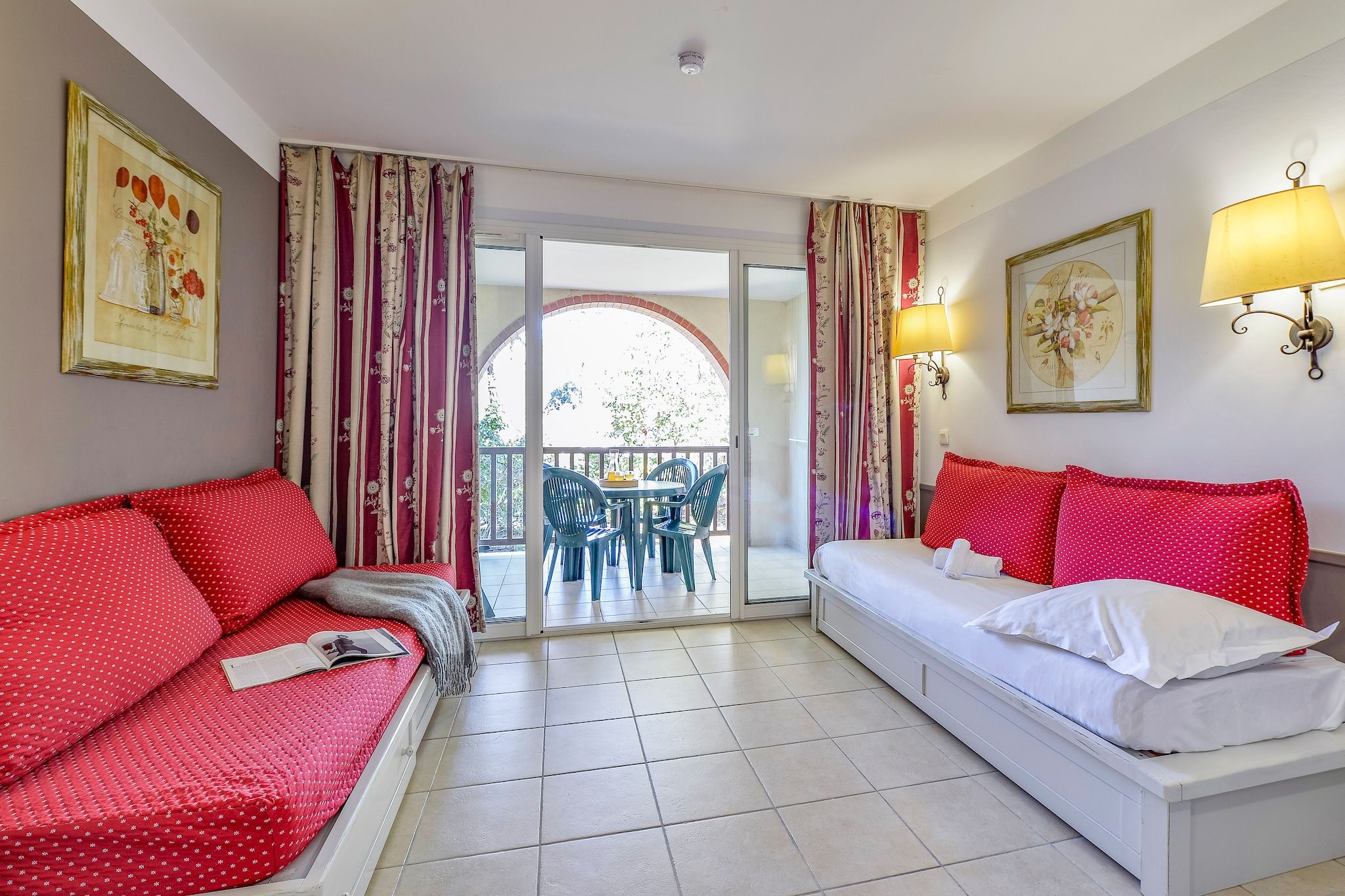 Ein Hotelzimmer mit Bett, einer Couch, einem Esstisch mit Stühlen und einem Balkon mit Vorhängen.