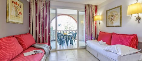 Una habitación de hotel con cama, sofá, mesa de comedor con sillas y balcón con cortinas.