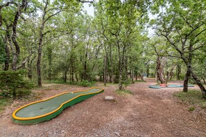 Une zone boisée avec un terrain de golf vert et jaune, et un trampoline bleu et orange.