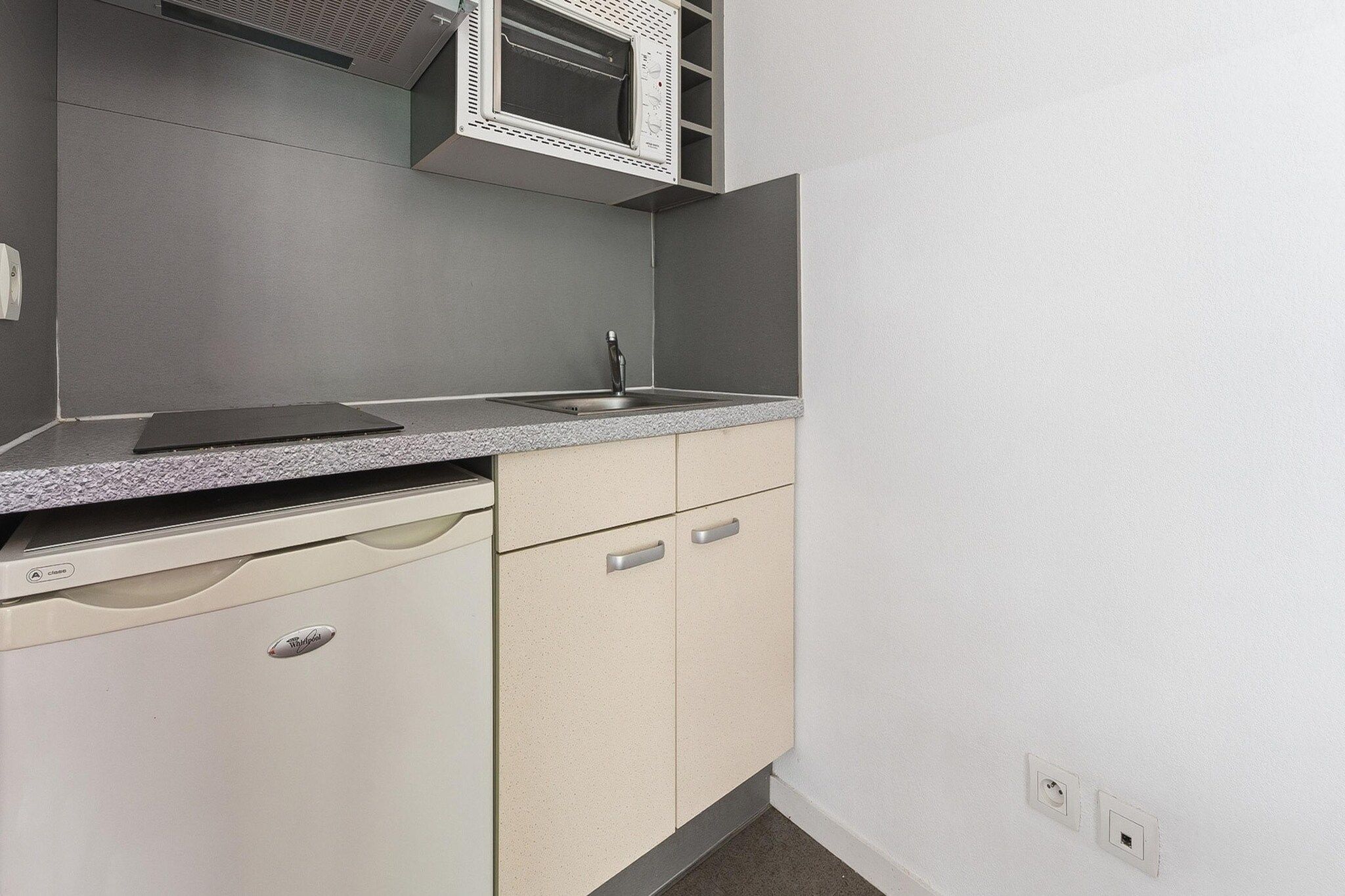 A compact kitchen with a dishwasher, a sink, and cabinets.
