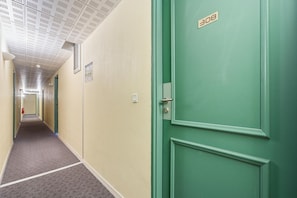 Ein Flur mit einer grünen Tür, auf der '308' steht, und einem an der Wand befestigten Feuerlöscher.