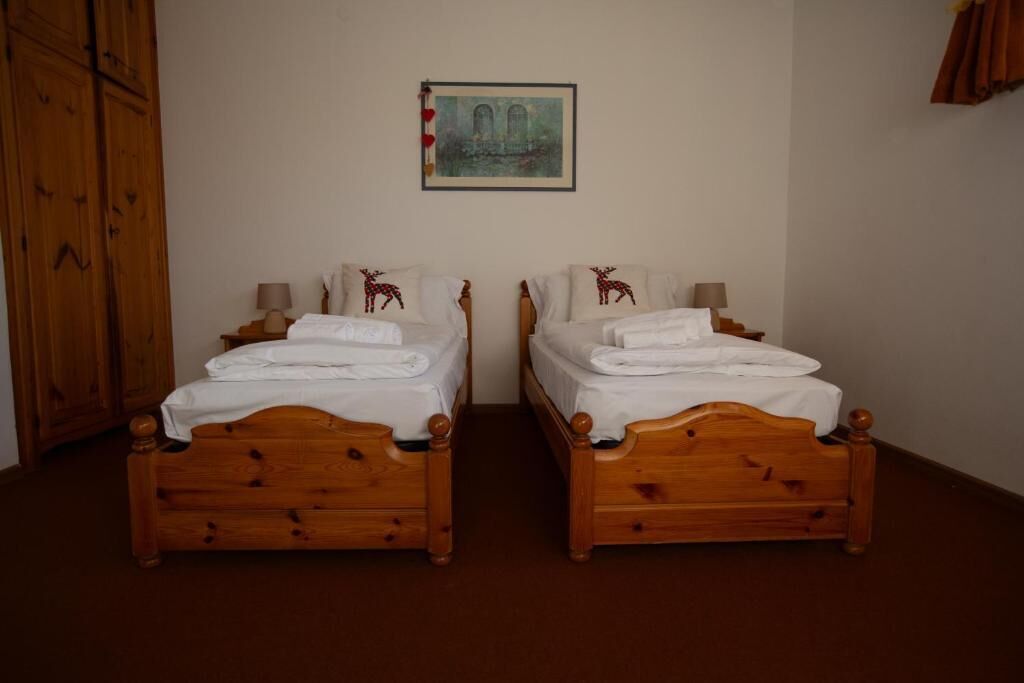 Una habitació amb dos llits de fusta, cadascun amb un coixí i una làmpada.