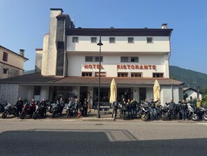 A building with a sign that reads 'HOTEL RISTORANTE' and a row of motorcycles parked in front. - Bike & Bikers Hotel (Ampezzo)