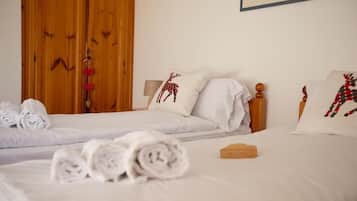 A hotel room with two beds, white linens, and decorative pillows with reindeer designs.