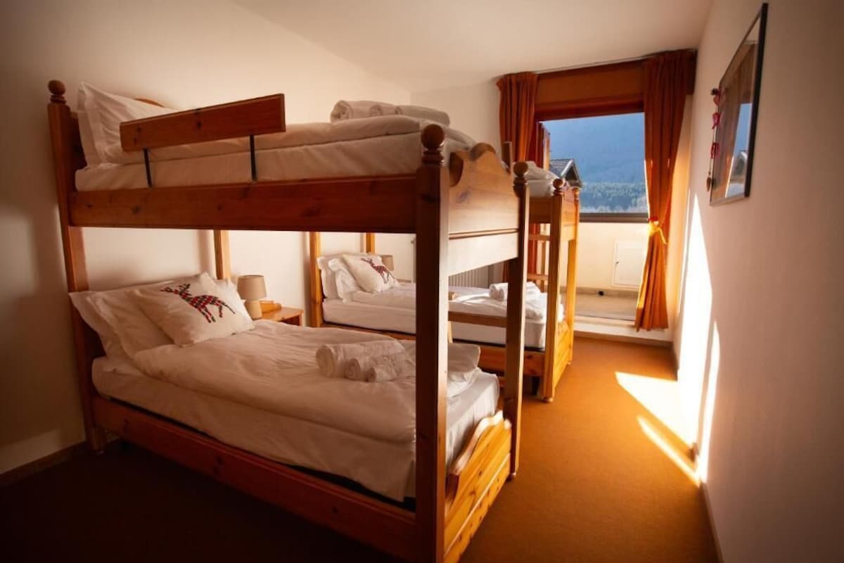 A bunk bed room with a view of the outdoors through a window.